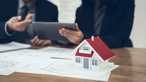 Zwei Personen mit Tablet in der Hand vor einem Modellhaus